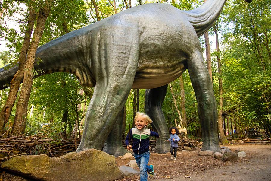 Kind met levensgrote dinosaurus